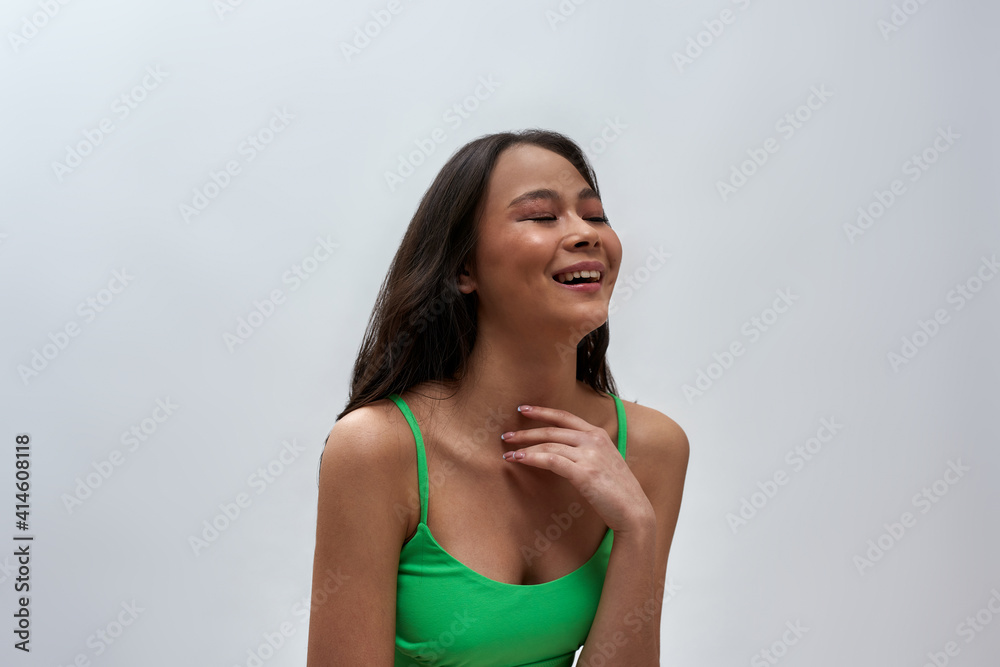 Joyful young woman wearing green underwear laughing aside, posing isolated over light background