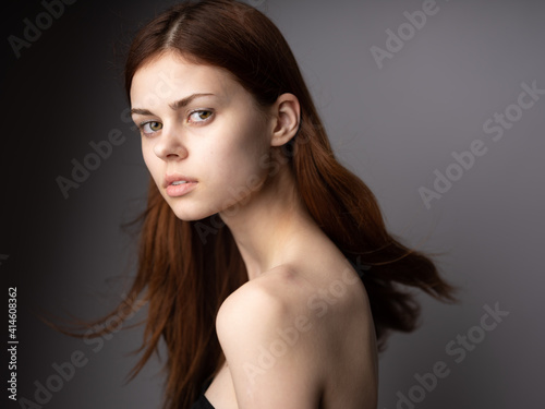 Side view of red-haired lady portrait on gray background beautiful face