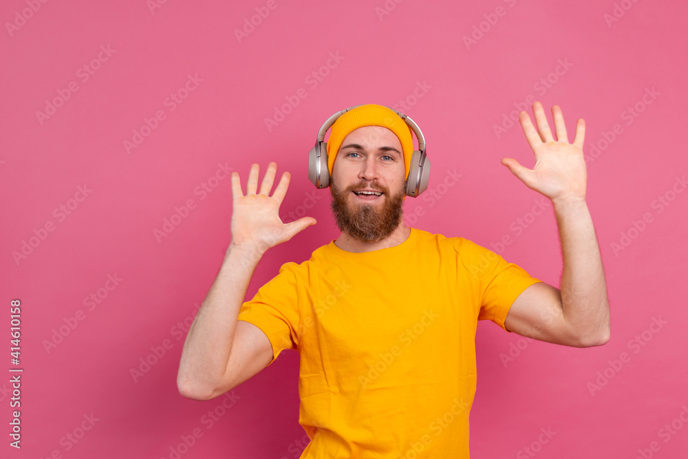 Handsome man in casual dancing with headphones isolated on pink background