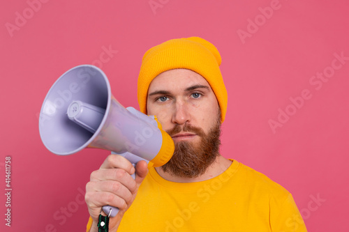 Serious european man with megaphone on pink background