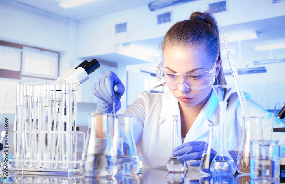 Fototapeta premium Laboratory concept background. Young scientist during experiment and using microscope in modern laboratory.