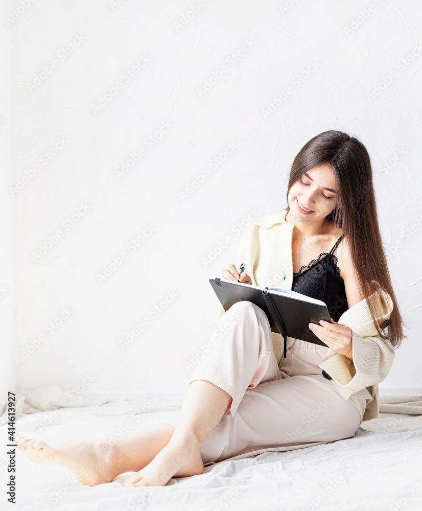 Beautiful woman in comfy home clothes writing notes sitting on the floor Beautiful woman in comfy home clothes writing notes sitting on the floor