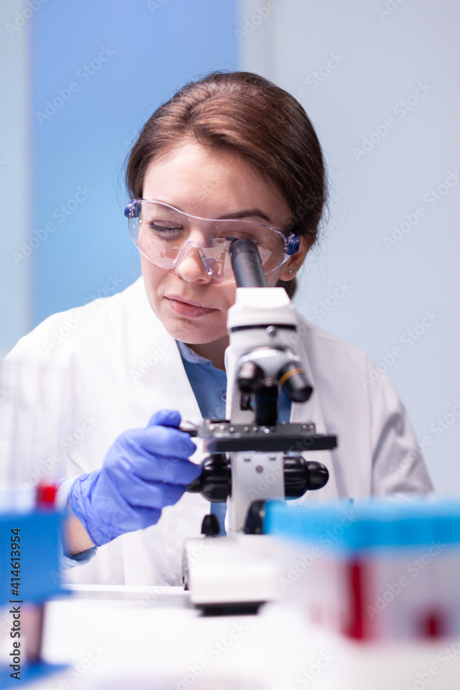 Caucasian woman scientist in white coat looking in high end microscope for pharmacy expertise. Modern laboratory for scientific research with professional equipment for studying virus and vaccine Caucasian woman scientist in white coat looking in high end microscope for pharmacy expertise. Modern laboratory for scientific research with professional equipment for studying virus and vaccine