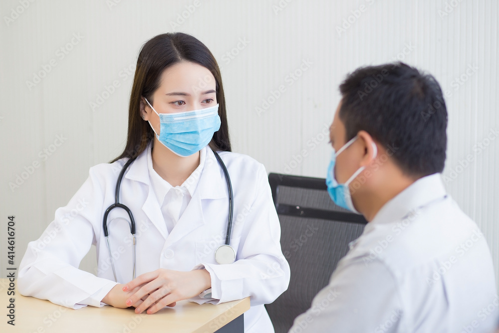 Asian female doctor talking with a man patient about his pain and symptom while they put on a face mask to prevent Coronavirus disease in hospital. Health care,pollution PM2.5,new normal concept. Asian female doctor talking with a man patient about his pain and symptom while they put on a face mask to prevent Coronavirus disease in hospital. Health care,pollution PM2.5,new normal concept.