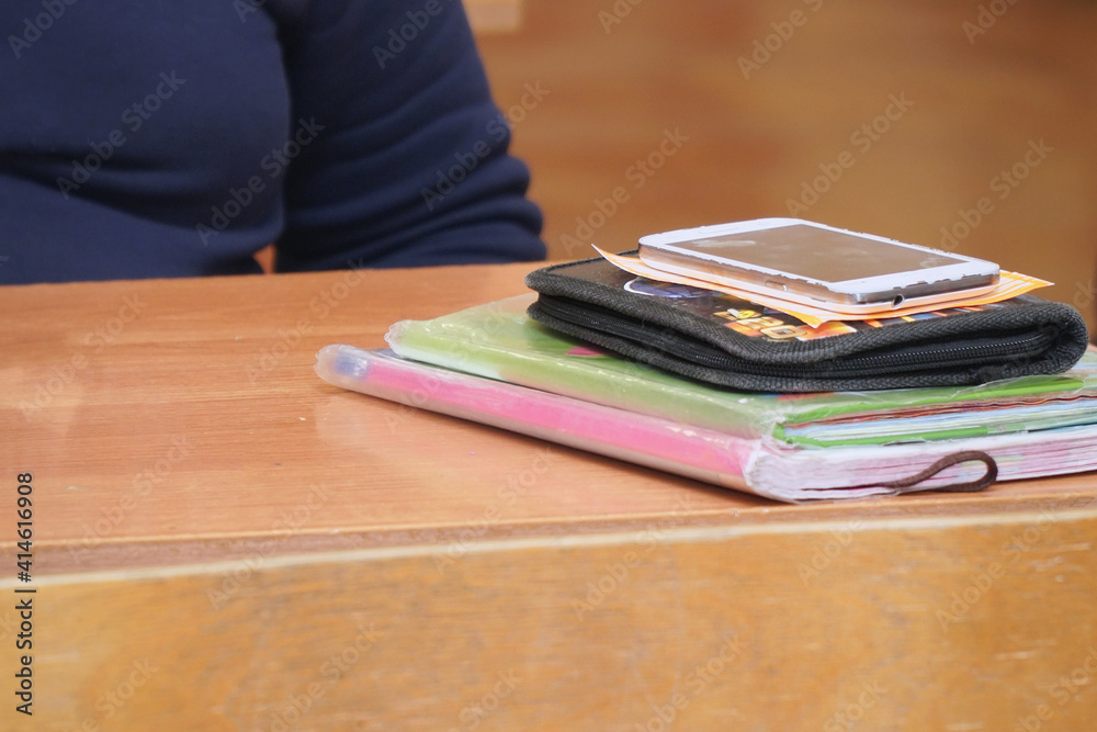 A desk in the classroom with textbooks and notebooks in small pile A desk in the classroom with textbooks and notebooks in small pile