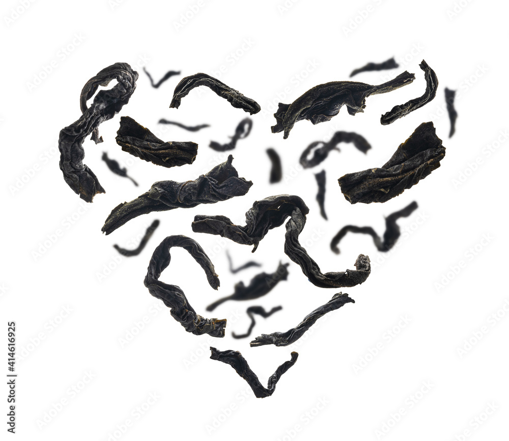 Dried black tea close up in the shape of a heart on white background Dried black tea close up in the shape of a heart on white background