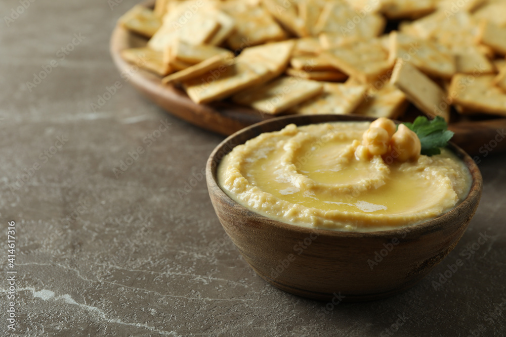 Tray with crackers and bowl of hummus on gray background Tray with crackers and bowl of hummus on gray background