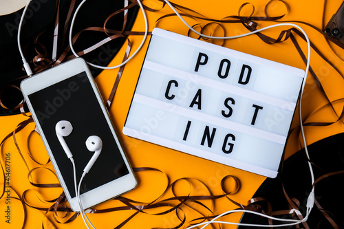 Podcasting lettering and vinyl record album audio cassette tape headphones and mobile phone. Millenial. Blogger, podcaster. Retro style photo