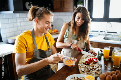 Canvas Print Happy young couple have fun in modern kitchen while preparing fresh food