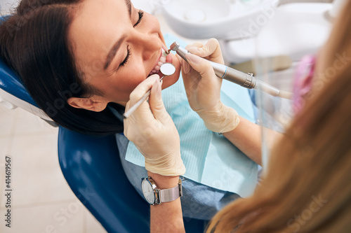 Positive delighted brunette woman sitting in dentistry chair