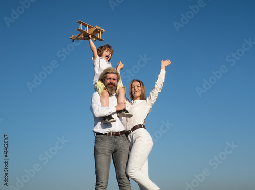 Family day outdoor. Kids love. Boy with toy airplane on fathers shoulders. Motherhood fatherhood. Son dad mother. Young parents with child.