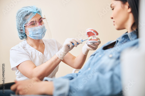 Competent stomatologist consulting her patient in cabinet