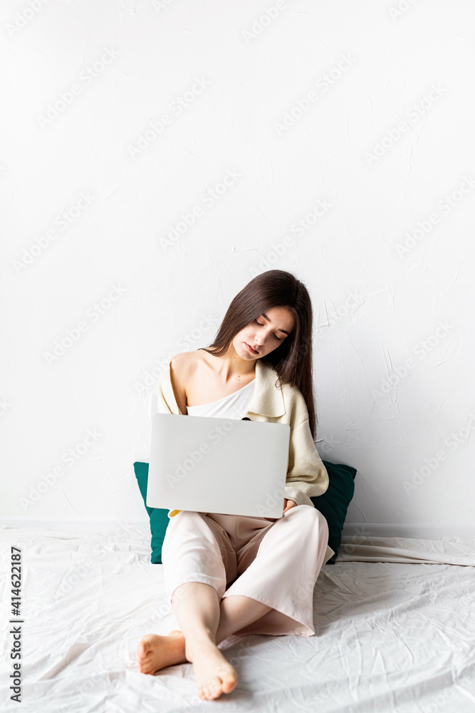 Beautiful young woman sitting on the floor and doing freelance project on laptop Beautiful young woman sitting on the floor and doing freelance project on laptop