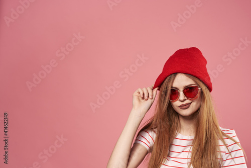 fashionable woman sunglasses and red hat studio pink background fashion