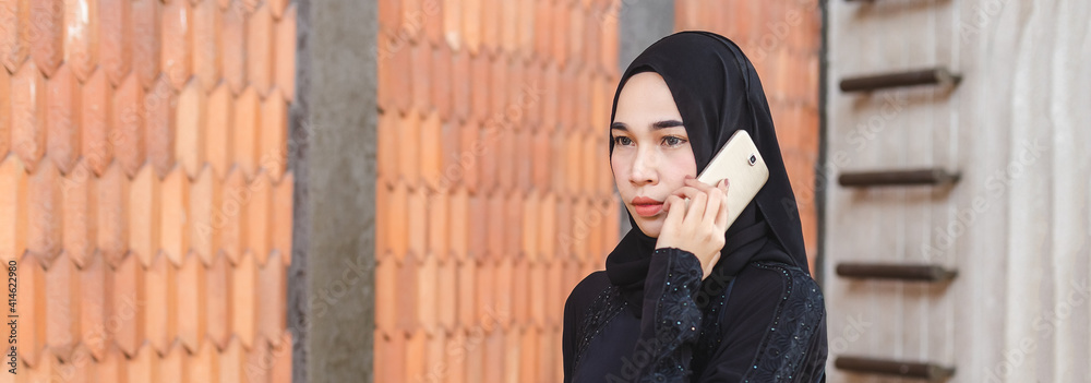 Fototapeta premium Muslim girl in hijab talkin a mobile phone.
