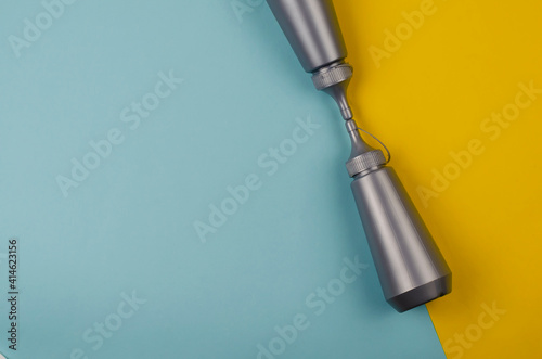 Two gray plastic bottles on a yellow and blue background.