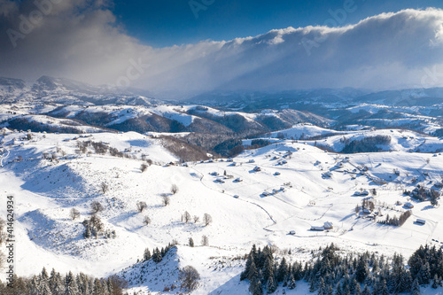 Aerial scenic rural view of Sirnea village at the bottom of Piatra-Craiului Mountains in freezing winter landscape from Romania