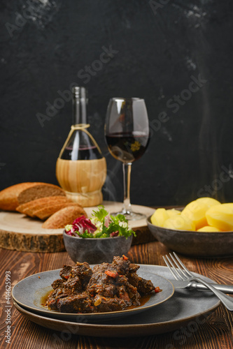 Beef ragout with potato, salad and wine