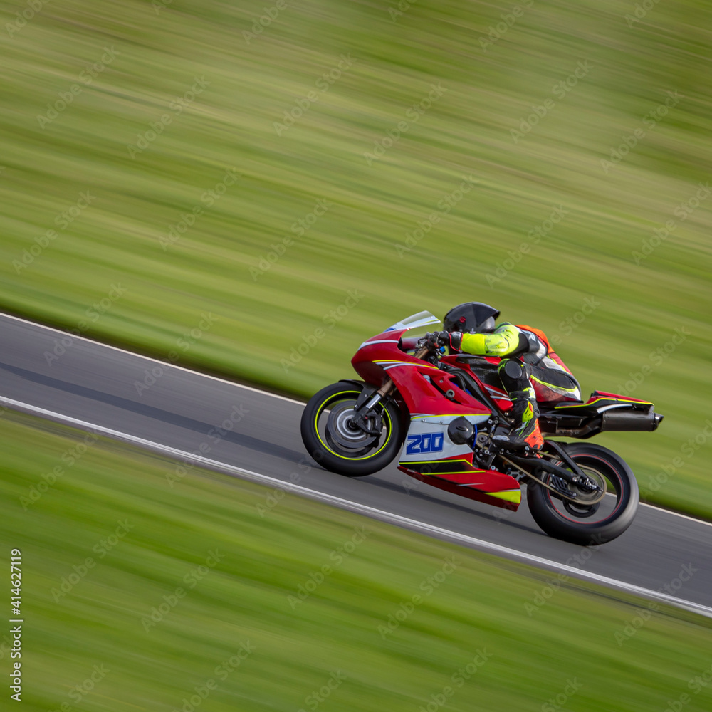 A panning shot of a racing motorbike as it circuits a track.