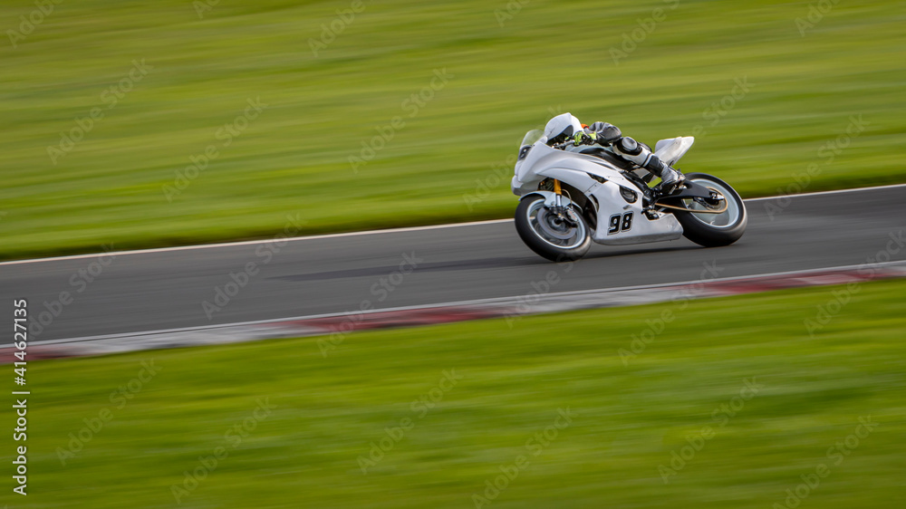 Fototapeta premium A panning shot of a racing motorbike as it circuits a track.