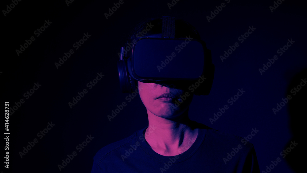 Girl with hands up wearing the VR headset goggles. Asian woman in glasses of virtual reality. The concept of futuristic. Digital VR glasses. Woman getting cyber experience using modern black color VR.
