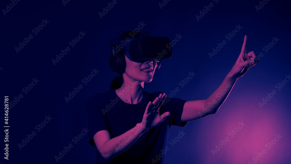 Girl with hands up wearing the VR headset goggles. Asian woman in glasses of virtual reality. The concept of futuristic. Digital VR glasses. Woman getting cyber experience using modern black color VR. Girl with hands up wearing the VR headset goggles. Asian woman in glasses of virtual reality. The concept of futuristic. Digital VR glasses. Woman getting cyber experience using modern black color VR.