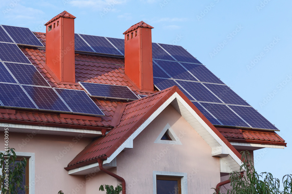 Fototapeta premium Solar panels on the roof of a private house with a chimney.