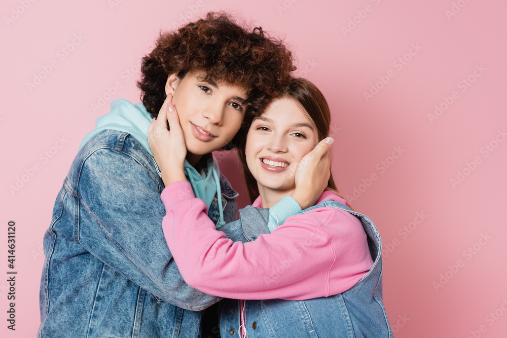 Happy teen couple embracing on pink background Happy teen couple embracing on pink background