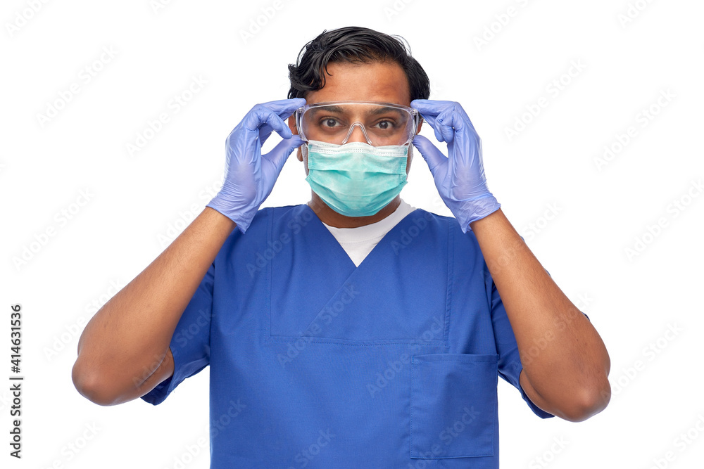 healthcare, profession and medicine concept - indian doctor or male nurse in blue uniform and face protective medical mask for protection from virus disease over white background healthcare, profession and medicine concept - indian doctor or male nurse in blue uniform and face protective medical mask for protection from virus disease over white background