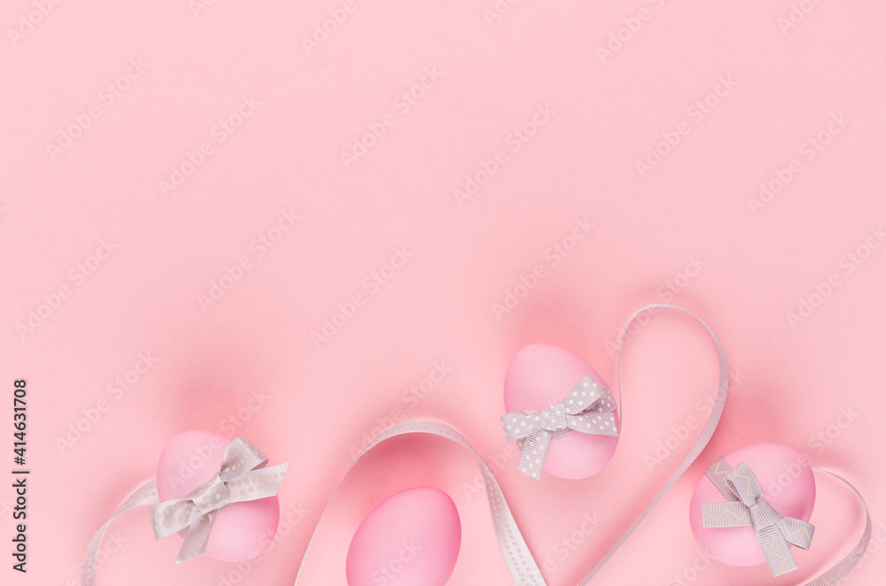 Cute easter eggs with grey curved ribbon lines as border on pastel pink background, copy space.