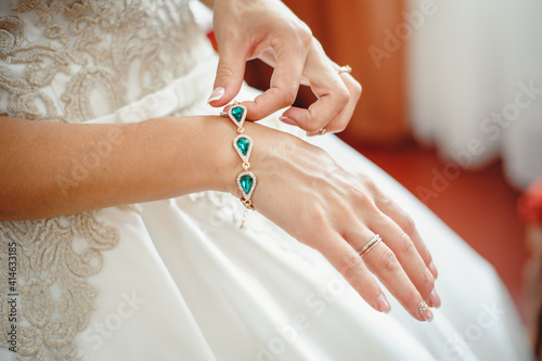 Beautiful elegant bride puts a bracelet on her hand, closeup. Girl put a bracelet on arm.Preparing the bride for the wedding ceremony.