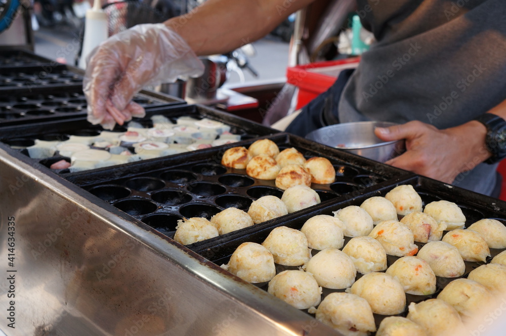 Employees are making Japanese food takoyaki. 