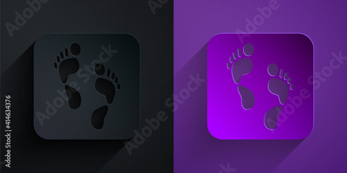 Paper cut Human footprint icon isolated on black on purple background. Trace of human foot. Paper art style. Vector.