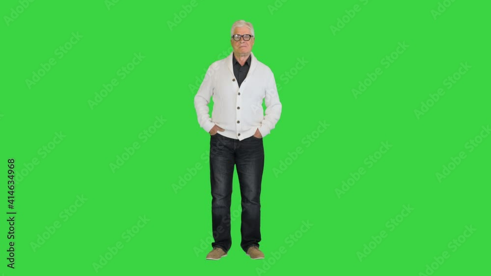 Senior man wearing a cardigan standing and looking to camera doing nothing on a Green Screen, Chroma Key. Senior man wearing a cardigan standing and looking to camera doing nothing on a Green Screen, Chroma Key.