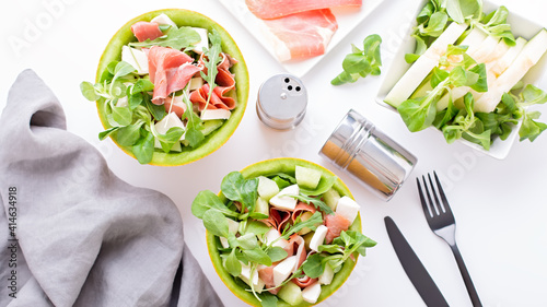 Summer mediterranean salad with ham and melon on white table top