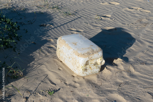 large industrial plastic bottle on the beach washed by the waves