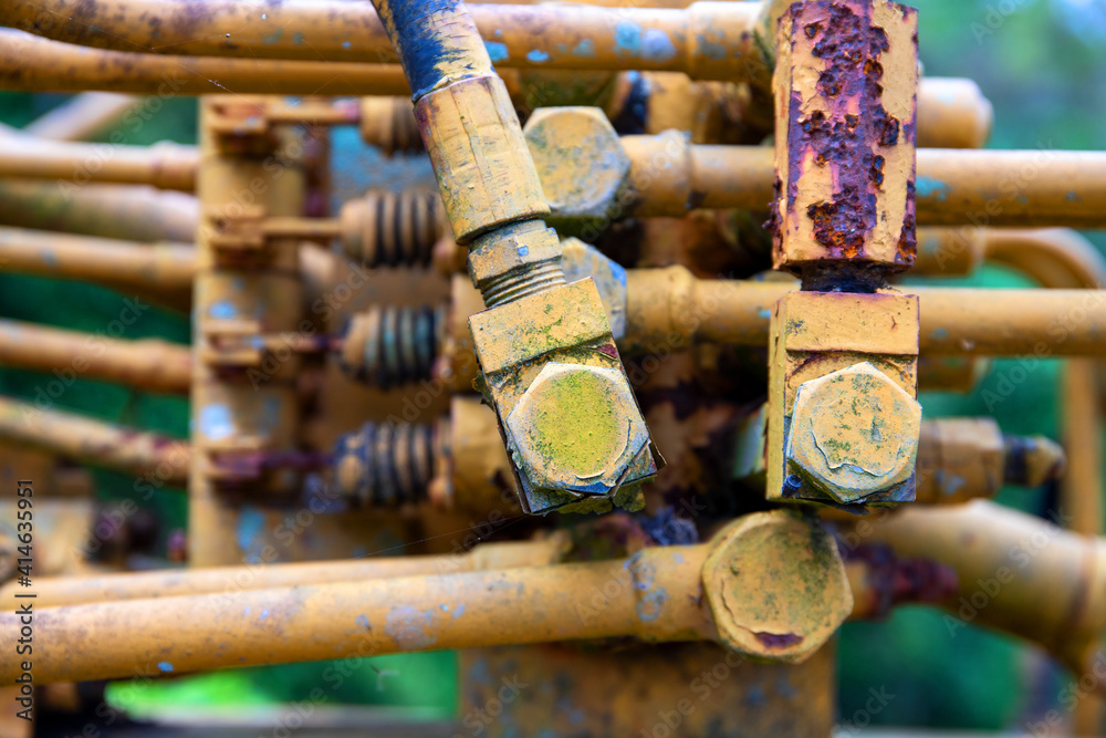 Old mechanism detail yellow painted special equipment closeup photo. Hydraulic pipe in red rust. Old mechanism detail yellow painted special equipment closeup photo. Hydraulic pipe in red rust.