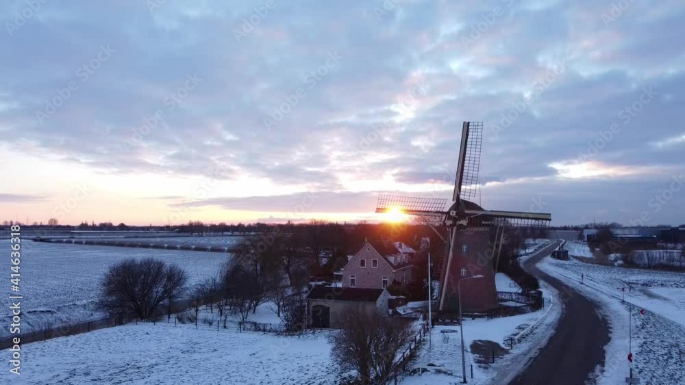 Sunset at a Dutch windmill in winter. Drone flies up camera remains focused on windmill. Sunset at a Dutch windmill in winter. Drone flies up camera remains focused on windmill.