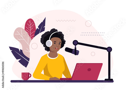 African-american radio host sitting in front of microphone. Young woman in headset working at the radio studio