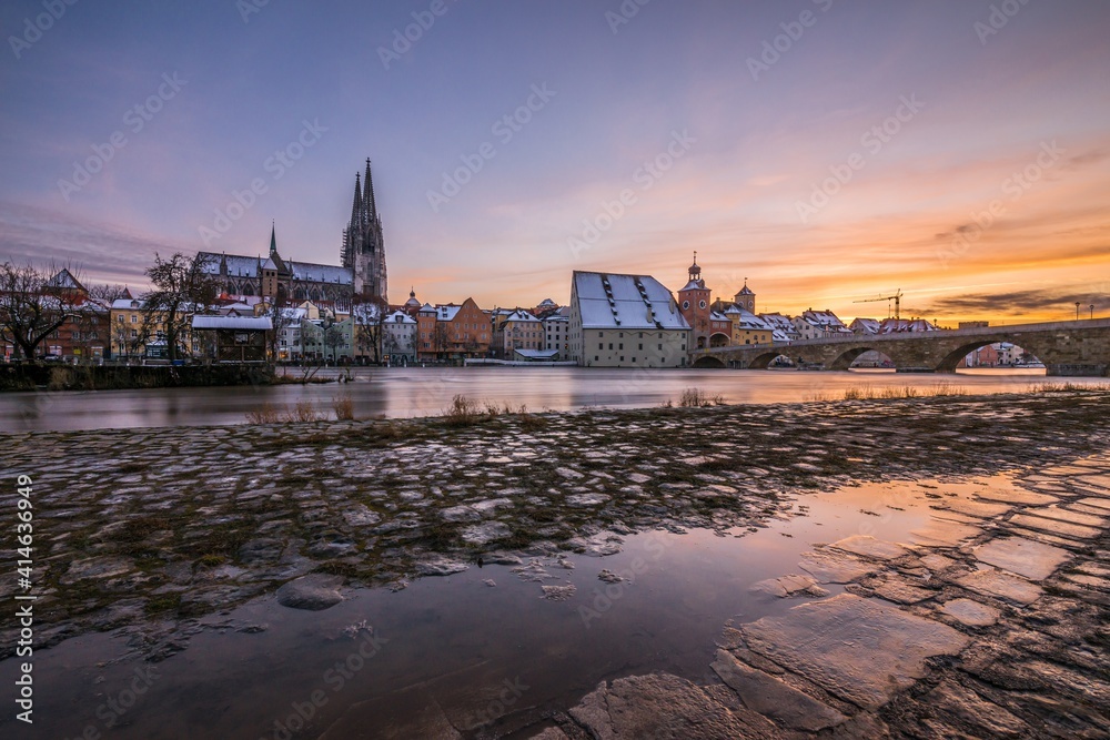 Sonnenuntergang während Hochwasser des Flusses Donau im Winter 2021 in Regensburg mit Blick auf den Dom die Altstadt und überschwemmte Promenade und der steinerne Brücke, Deutschland Sonnenuntergang während Hochwasser des Flusses Donau im Winter 2021 in Regensburg mit Blick auf den Dom die Altstadt und überschwemmte Promenade und der steinerne Brücke, Deutschland