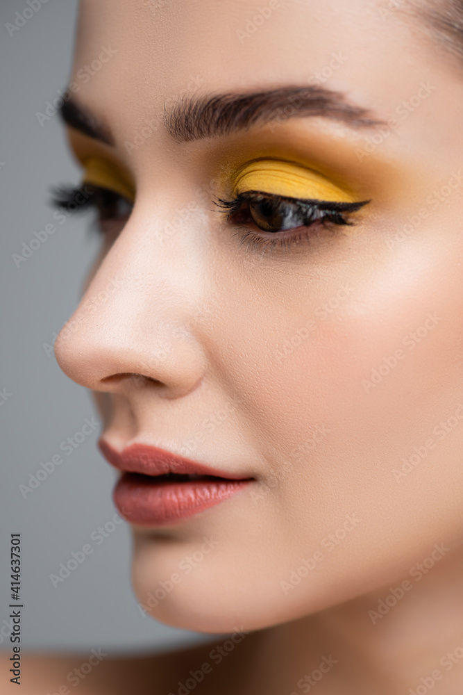 close up of young woman with yellow eyeshadow looking away isolated on grey close up of young woman with yellow eyeshadow looking away isolated on grey