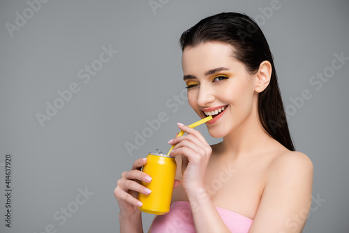 brunette woman drinking soft drink with straw isolated on grey