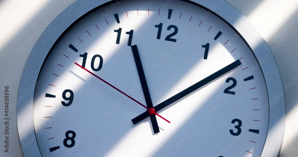 Sun and sky reflecting in the watch during the time passing by. Time lapse on a modern wall clock at noon. Wall clock show the running time. Close up to a wall clock, with running time pointer. Sun and sky reflecting in the watch during the time passing by. Time lapse on a modern wall clock at noon. Wall clock show the running time. Close up to a wall clock, with running time pointer.