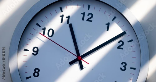 Sun and sky reflecting in the watch during the time passing by. Time lapse on a modern wall clock at noon. Wall clock show the running time. Close up to a wall clock, with running time pointer. 
