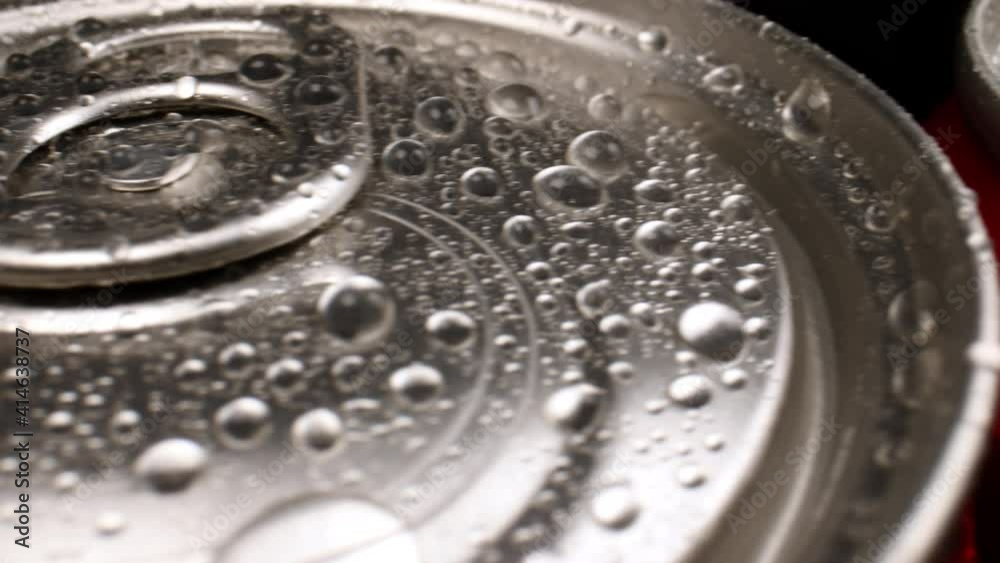 The camera pans along the cans of cola, close-up. The camera pans along the cans of cola, close-up.