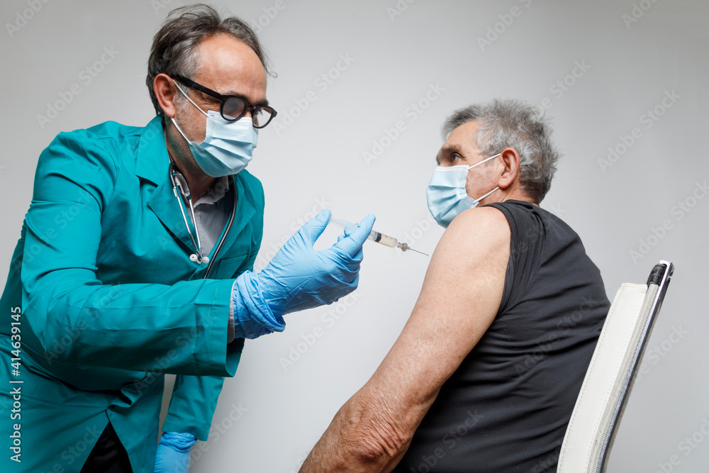 inflation boat Darken Dottore con in camice e mascherina protettiva prepara una siringa con il  vaccino che sta per iniettare ad un paziente anziano pronto a ricevere la  puntura. Stock Photo | Adobe Stock