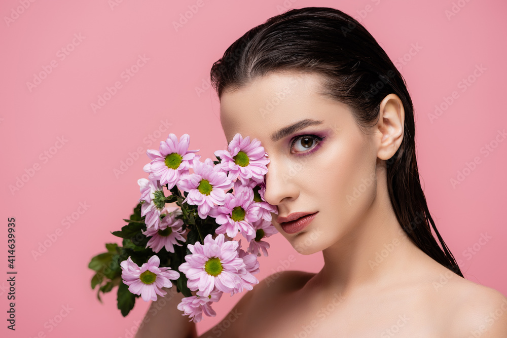 young sensual woman with bare shoulders holding flowers isolated on pink