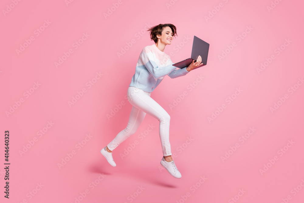Full length photo of cute pretty young woman wear sweater jumping chatting modern gadget isolated pink color background Full length photo of cute pretty young woman wear sweater jumping chatting modern gadget isolated pink color background