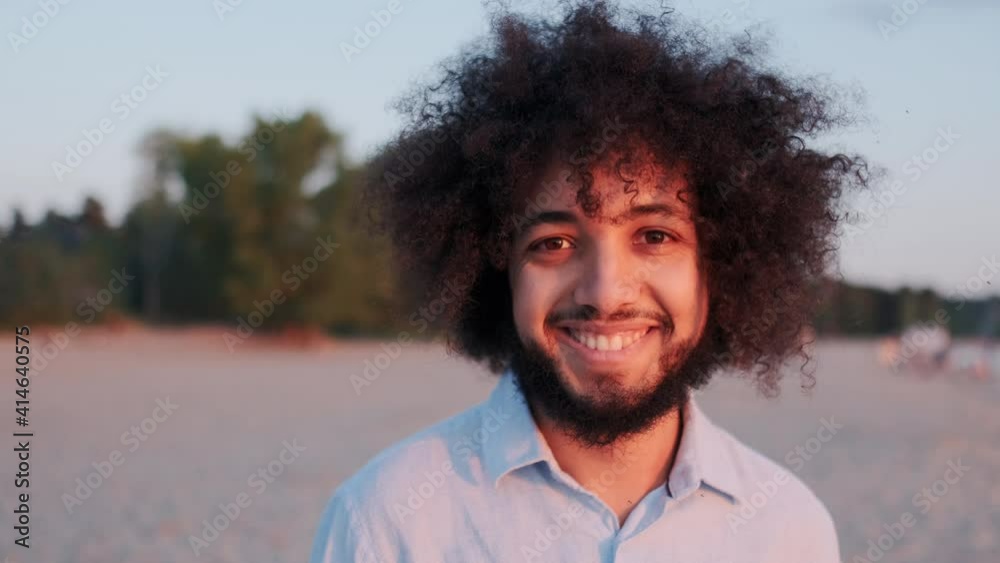 Closeup Face of Charismatic Latin American Curly Man Looking in Camera. Fortunate Arab Man Standing in Sunset Light. Concept of Harmony, Freedom and Success. Closeup Face of Charismatic Latin American Curly Man Looking in Camera. Fortunate Arab Man Standing in Sunset Light. Concept of Harmony, Freedom and Success.