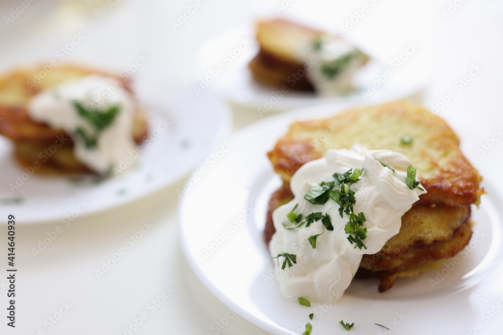 Potato pancakes with sour cream and herbs on plate Potato pancakes with sour cream and herbs on plate